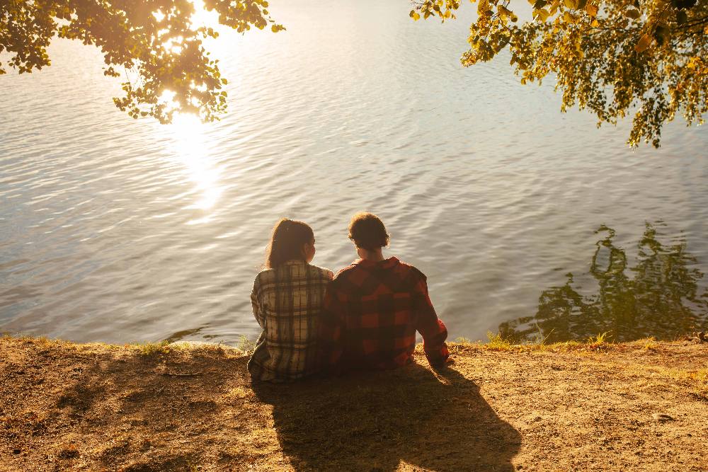 Casal à beira do lago no Vistta Castanho ao pôr do sol